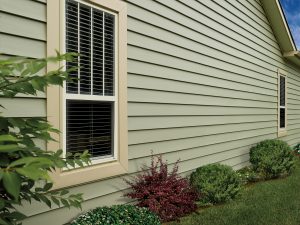 The side of a home featuring green fiber cement siding and a double-hung window.