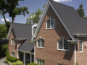 A two-story home with a brick exterior and a new asphalt shingle roofing system.