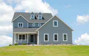 A large single-family home with a gray shingle roof and blue vinyl siding.