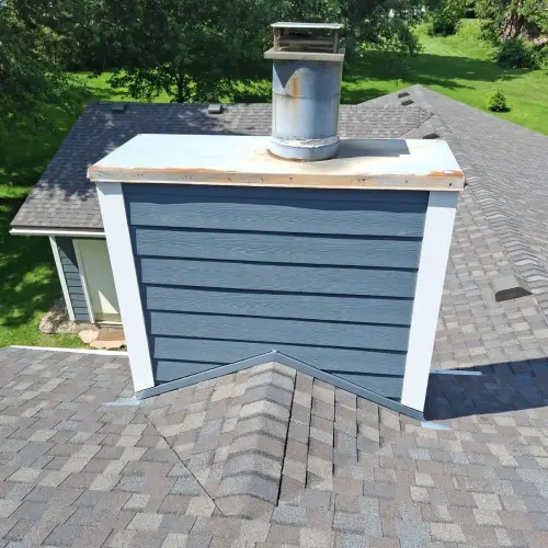 Brick chimney showing chimney flashing and surrounding shingles by Wright at Home Roofing & Exteriors in Minnesota