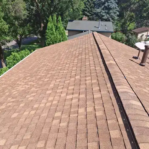Asphalt roof ridge line with brown shingles by Wright at Home Roofing & Exteriors in Minnesota