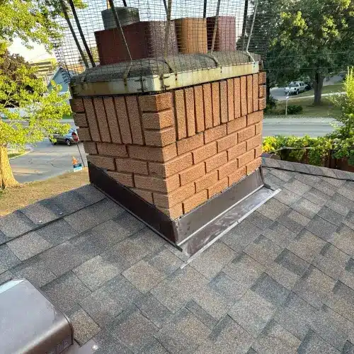 Roof valley meeting chimney with flashing and asphalt shingles by Wright at Home Roofing & Exteriors in Minnesota