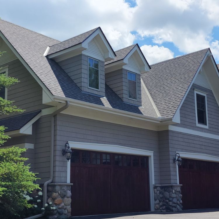 Suburban home with gray shingle siding and a dark gray roof that had a siding repair by siding repair contractors in Minneapolis, MN