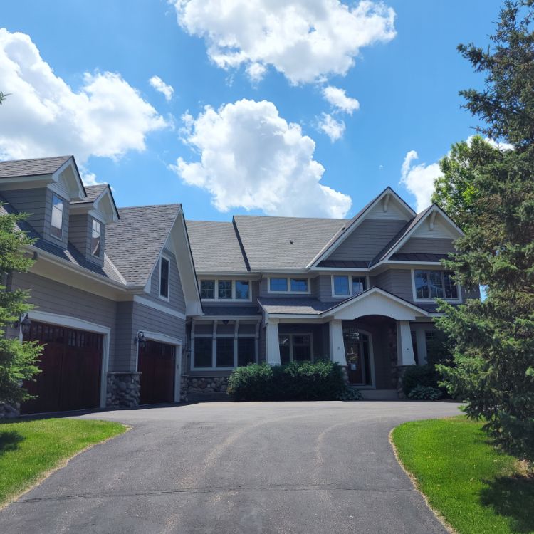 Suburban home with gray shingle siding and a dark gray roof that had a siding repair by siding repair contractors in Minneapolis, MN