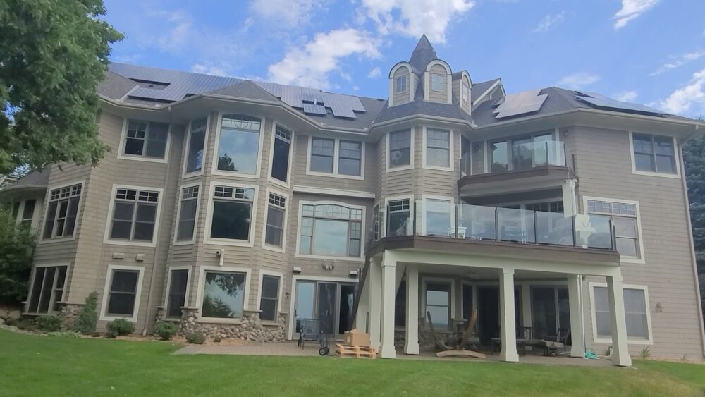 Large, multi-level house with light beige or tan siding and numerous windows of varying sizes made by Wright at Home Roofing & Exteriors in Minneapolis, MN