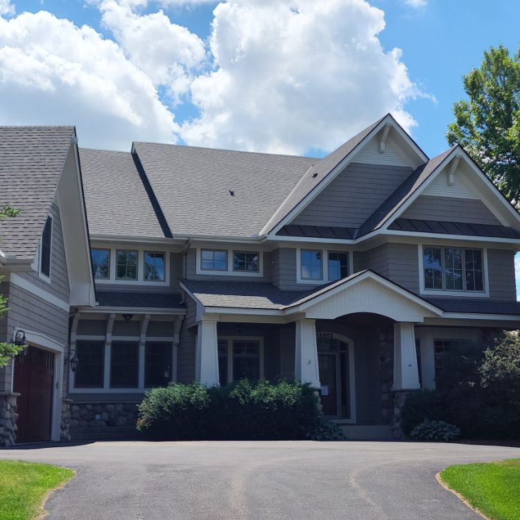 Suburban home with gray shingle siding and a dark gray roof that had a siding repair by siding repair contractors in Minneapolis, MN