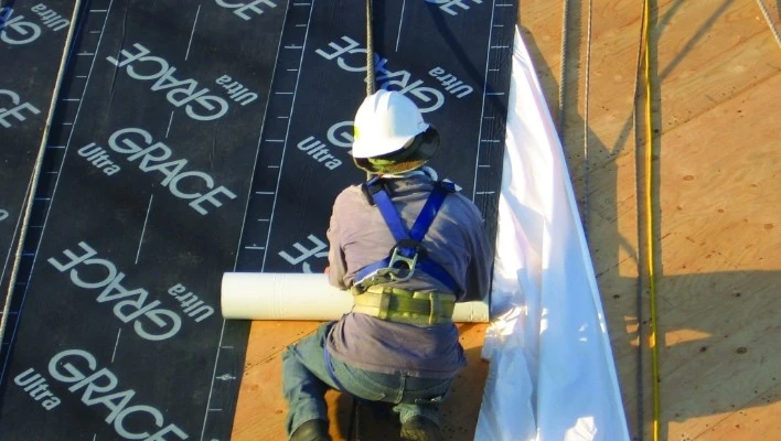 A residential roofing contractor on top of a roof in a process of storm damage repair in Minneapolis, MN