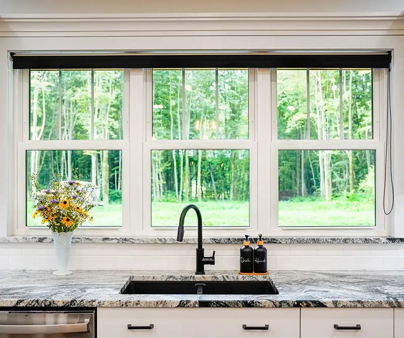 Kitchen with a large window overlooking a green forest that had a recent marvin window installation in Minneapolis, MN