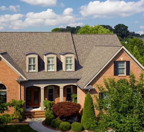 Two-story brick house with a brown shingle roof under a blue sky by a residential roofing contractor in Minneapolis, MN