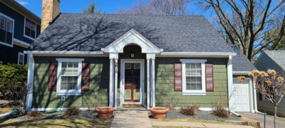 A small, single-story green house featuring Marvin window replacements at Wright at Home Roofing & Exteriors Minneapolis, MN.