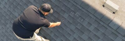 man performing a roof inspection on top of a black shingle roof by Wright at Home Roofing & Exteriors in Minneapolis, MN