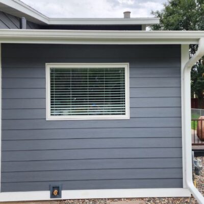 Dark gray James Hardie lap siding on a house exterior, with a white-framed window and white trim installed by a window contractor in Minneapolis, MN