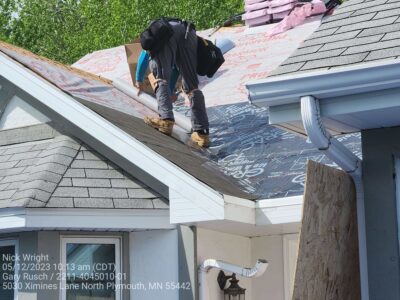 Roofer rolling out underlayment for shingle roof replacement by Wright at Home Roofing & Exteriors in Maple Grove