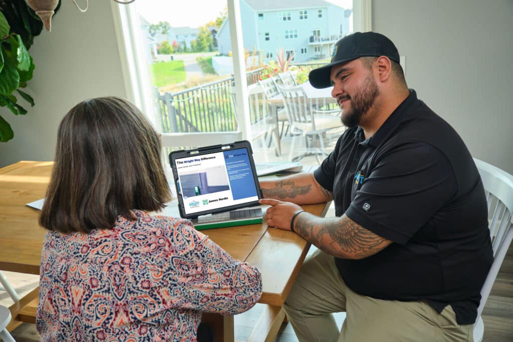 Wright at Home Roofing & Exteriors team member meeting with a female client inside a home at a table discussing exterior project in Minneapolis, MN.