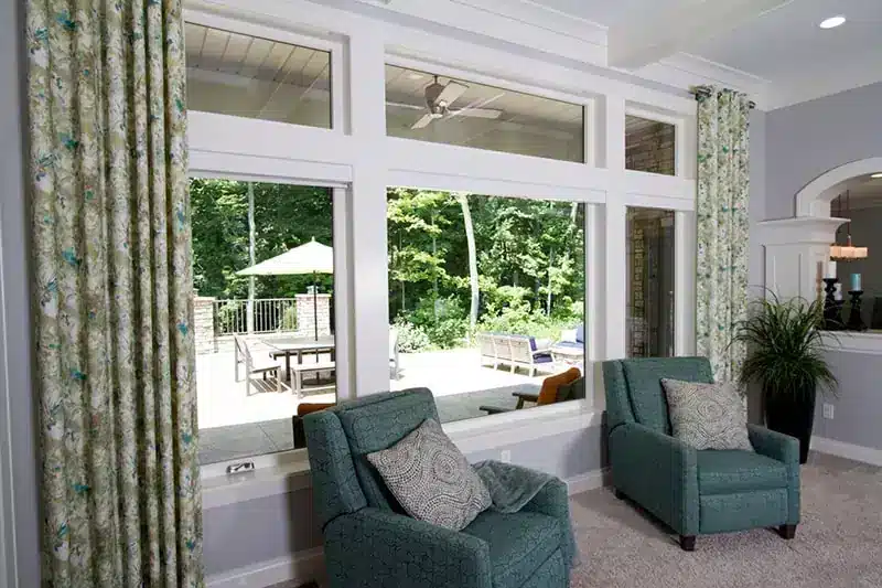 A bright living room with large provia windows offering a view of a patio and wooded area in Minneapolis, MN
