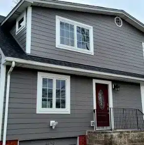 A two-story house with gray horizontal siding with white windows, made by window contractors in Minneapolis, MN