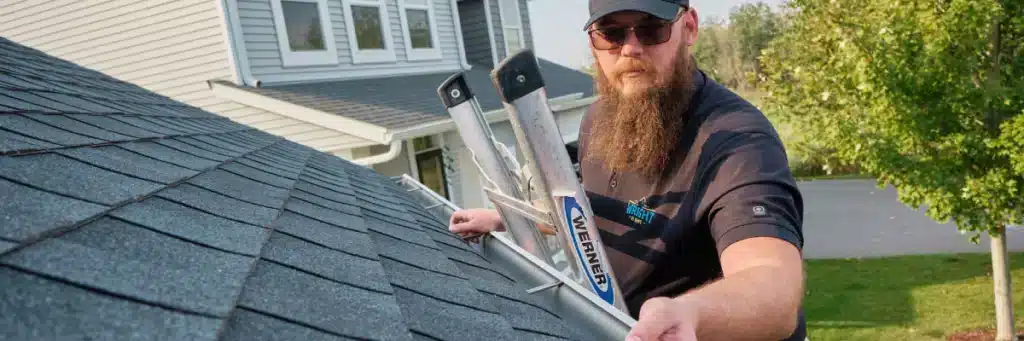 Roofing technician inspecting asphalt shingles and gutters to compare roof estimates in Minneapolis