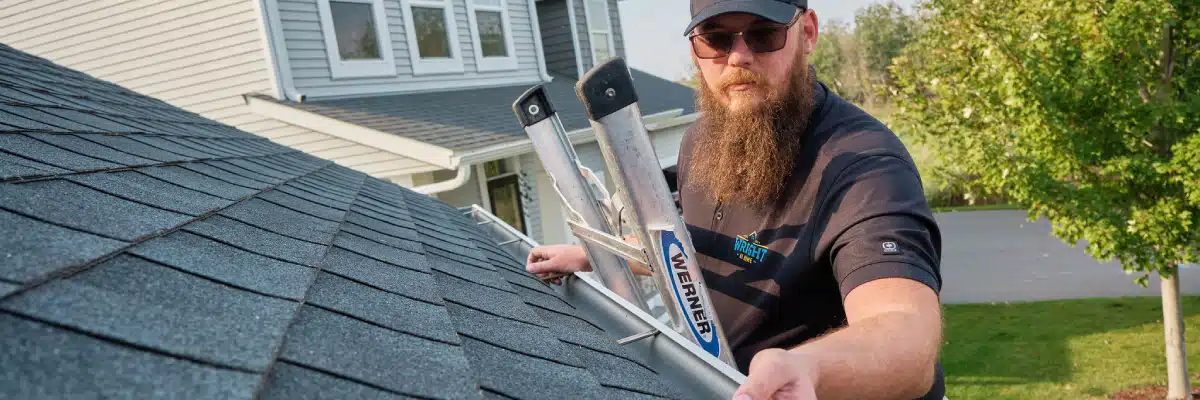 Roofing technician inspecting asphalt shingles and gutters to compare roof estimates in Minneapolis