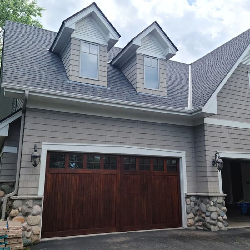 A two-story house with gray shingles, fiber cement siding installation, and stone accents Wright at Home Roofing & Exteriors Minneapolis, MN..