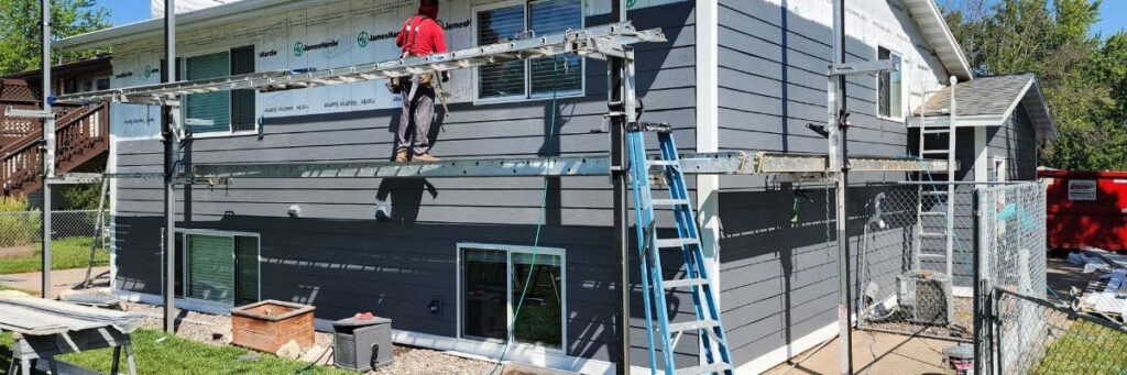 window contractors on a two-story house undergoing window and siding installation in Minneapolis, MN