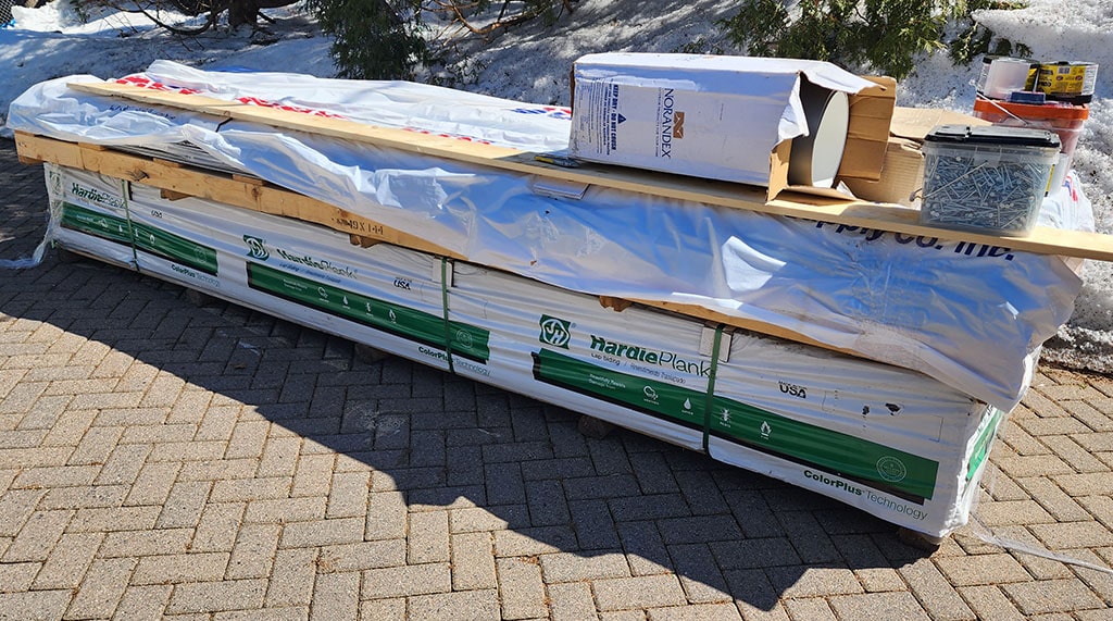 A stack of HardiePlank siding wrapped in plastic.