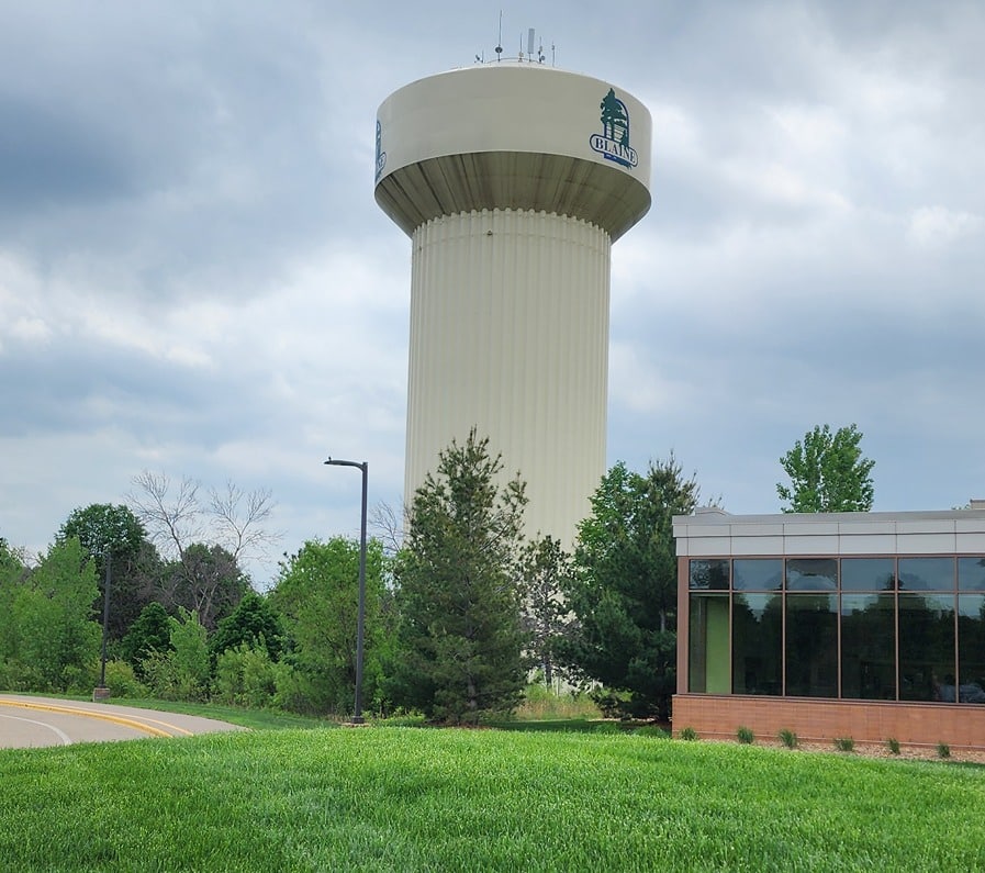 Blaine water tower surrounded by greenery and commercial buildings, improved by Wright at Home in Blaine