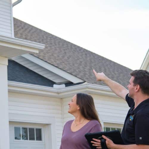 Wright at Home Roofing & Exteriors employee assessing siding and roofing with homeowner in Minneapolis, MN