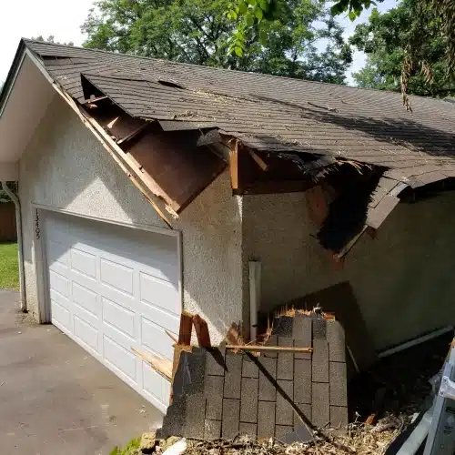 Garage roof in Minneapolis, MN with severe shingle loss, exposed decking, and collapsed structure from hail damage, illustrating hail damage roof Minnesota by Wright at Home Roofing & Exteriors