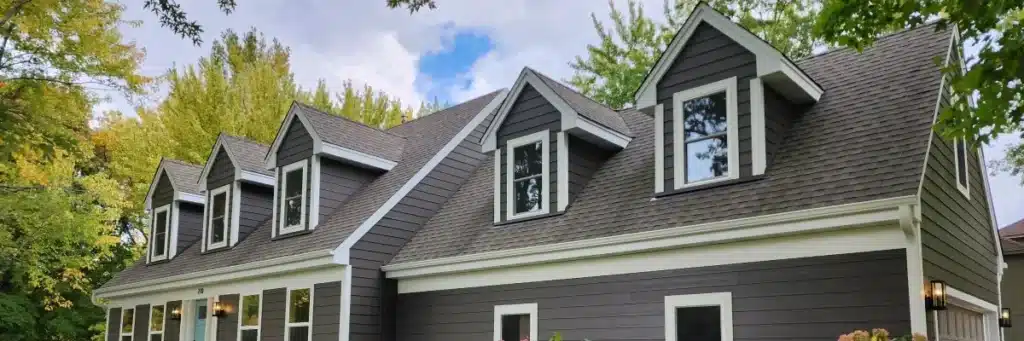 Modern two-story Minneapolis home with new asphalt shingle roof, gray siding, beautiful curb appeal, and lush landscaping, reflecting positive roofing company reviews Minneapolis by Wright at Home Roofing & Exteriors
