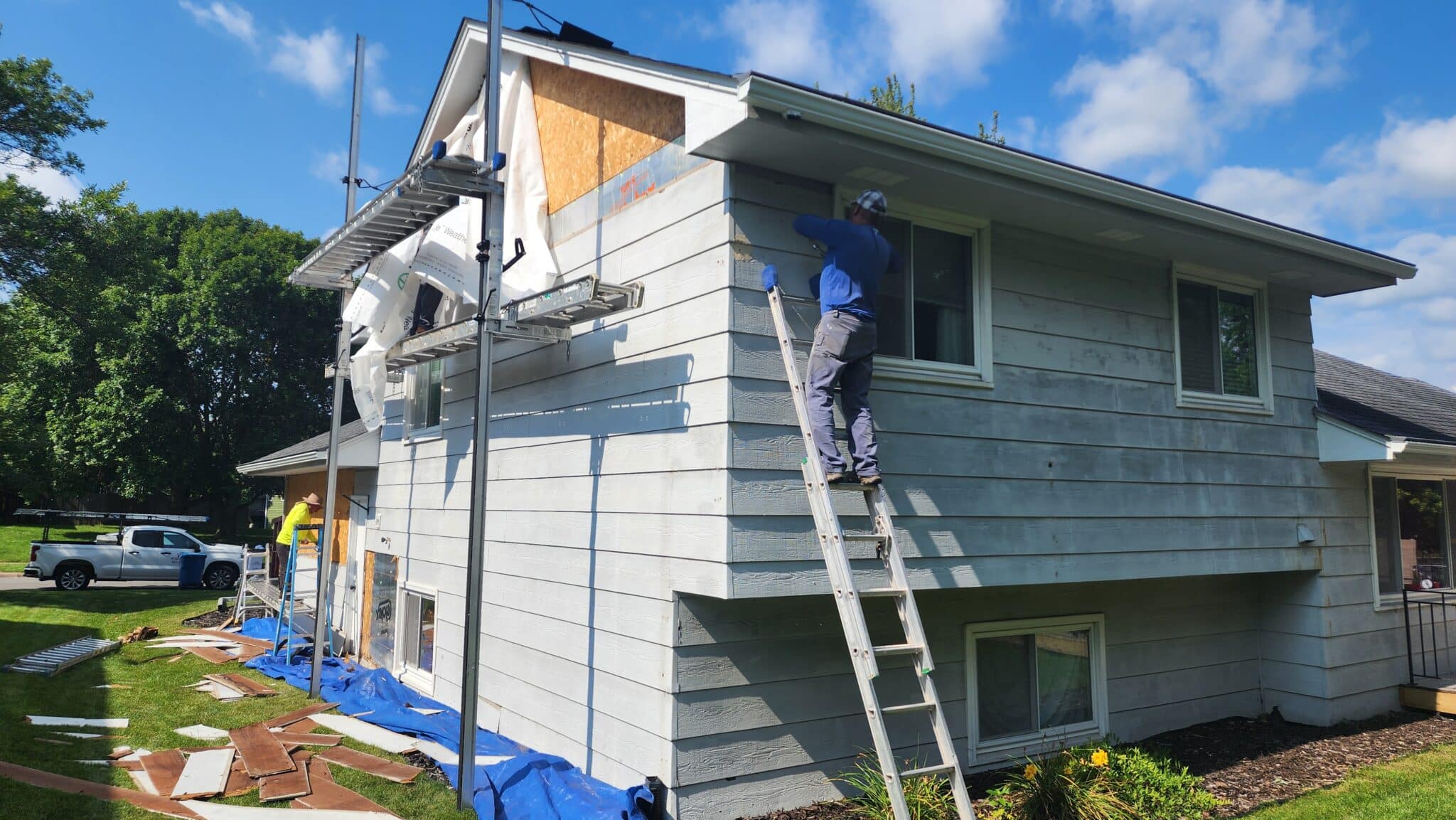 Wright at Home Roofing and Exteriors crews replacing the siding on a home using a grey color plank siding in Minneapolis.