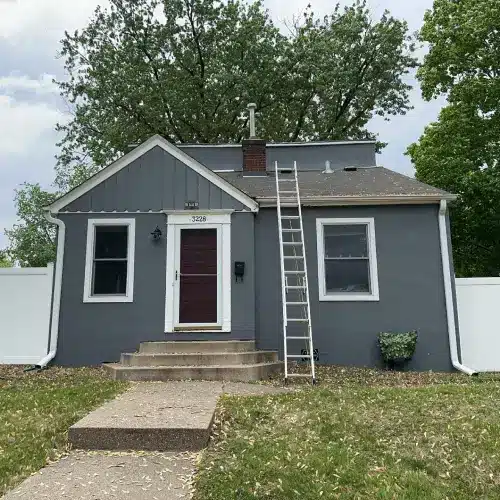 Gray residential home with new roofing and siding in St. Louis Park, MN, featuring a ladder set up for exterior renovation work.