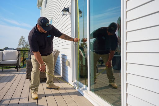 Roofing contractor measuring sliding patio door frame for installation by Wright at Home Roofing & Exteriors in Crystal