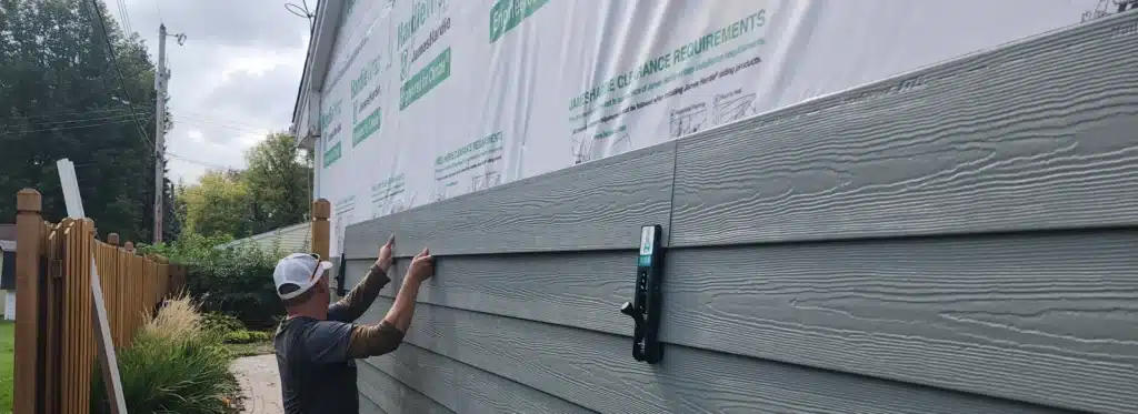 Contractor installing energy-efficient siding panels on a Minneapolis home by Wright at Home Roofing & Exteriors