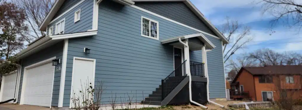 Blue two-story home featuring new siding installation by Wright at Home Roofing & Exteriors in Minneapolis