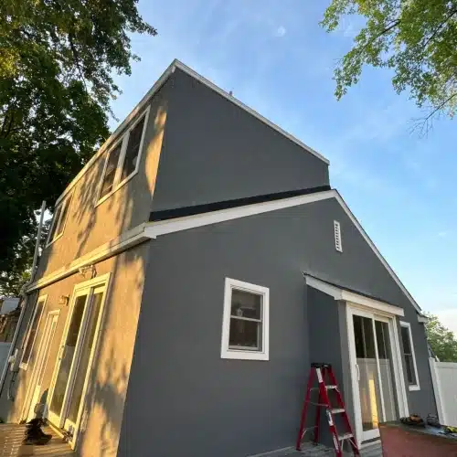Stucco exterior renovation in gray tone with white-trimmed windows by Wright at Home Roofing & Exteriors