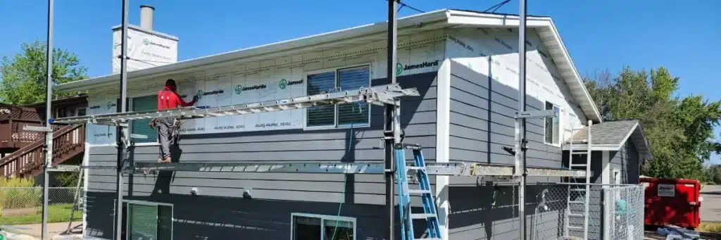 Construction team installing James Hardie siding and completing window replacement by Wright at Home Roofing & Exteriors in Blaine MN