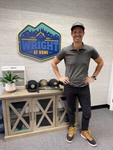 Addison Kaasa of Wright at Home Roofing & Exteriors inside of their office smiling in front of their office sign