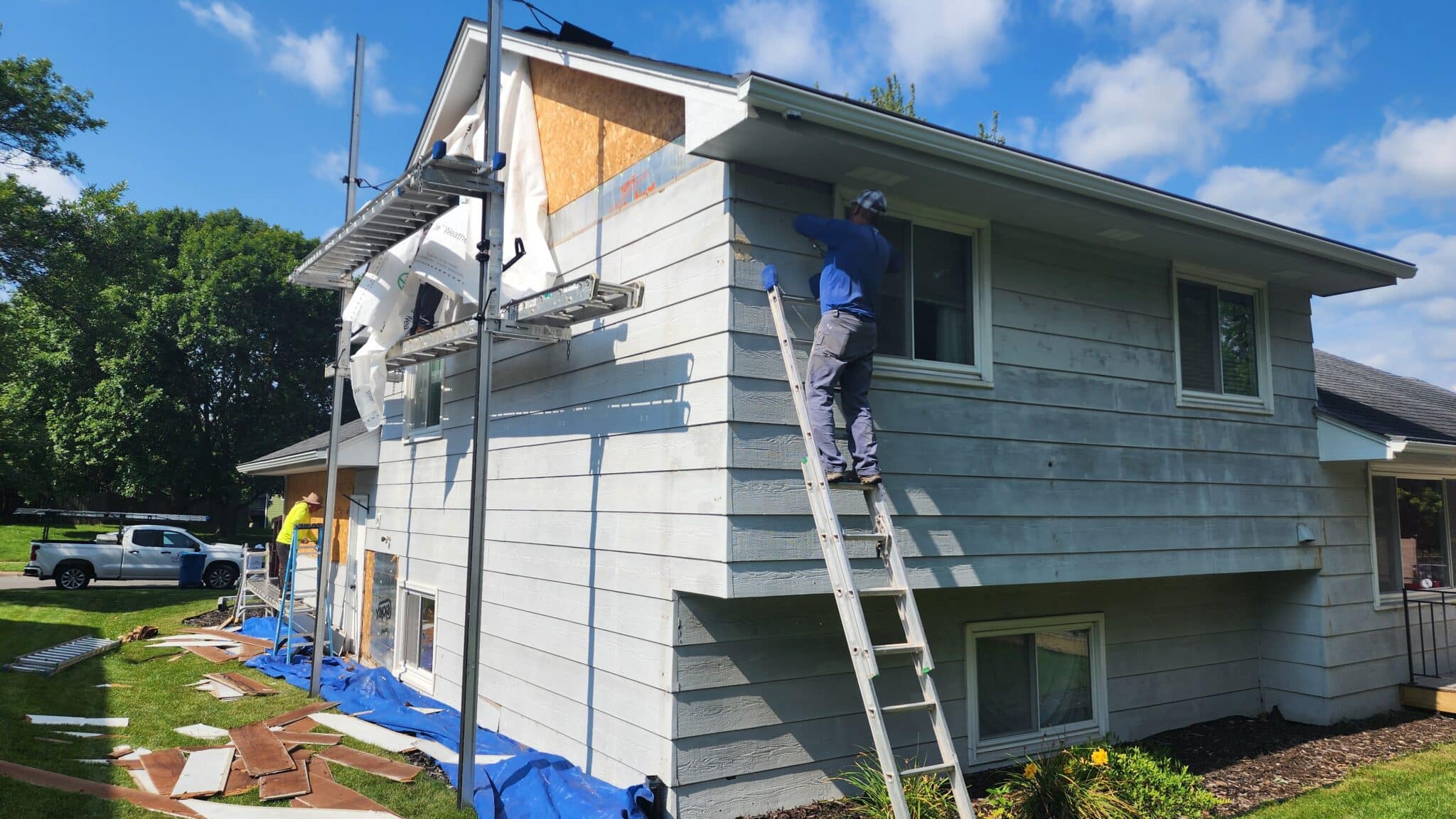 Workers replacing siding during modern monochrome transformation exterior renovation in Blaine, MN by Wright at Home Roofing & Exteriors