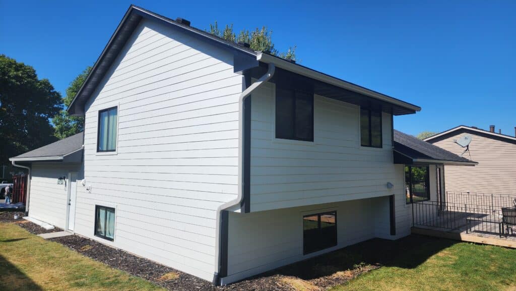 Modern home exterior with fresh light gray siding and black-framed windows, showing a completed project to replace siding and windows together in Blaine, Minnesota by Wright At Home