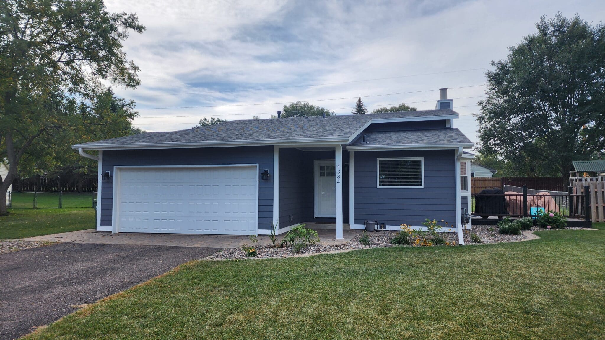 Single-story house with dark slate gray lap siding, crisp white trim, and a white garage door, showing a completed project to replace siding and windows together in Blaine, Minnesota by Wright At Home